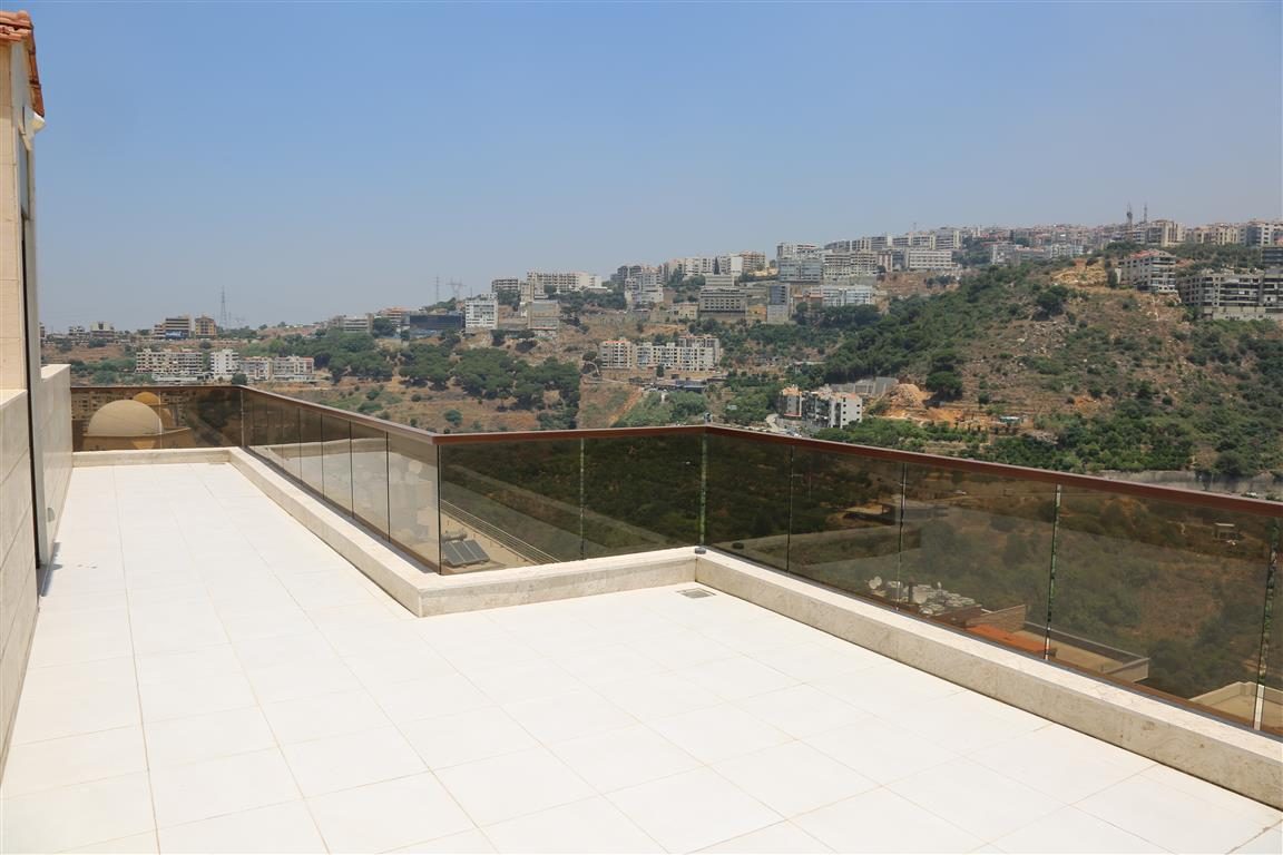 Wide rooftop terrace with glass railing over the valley