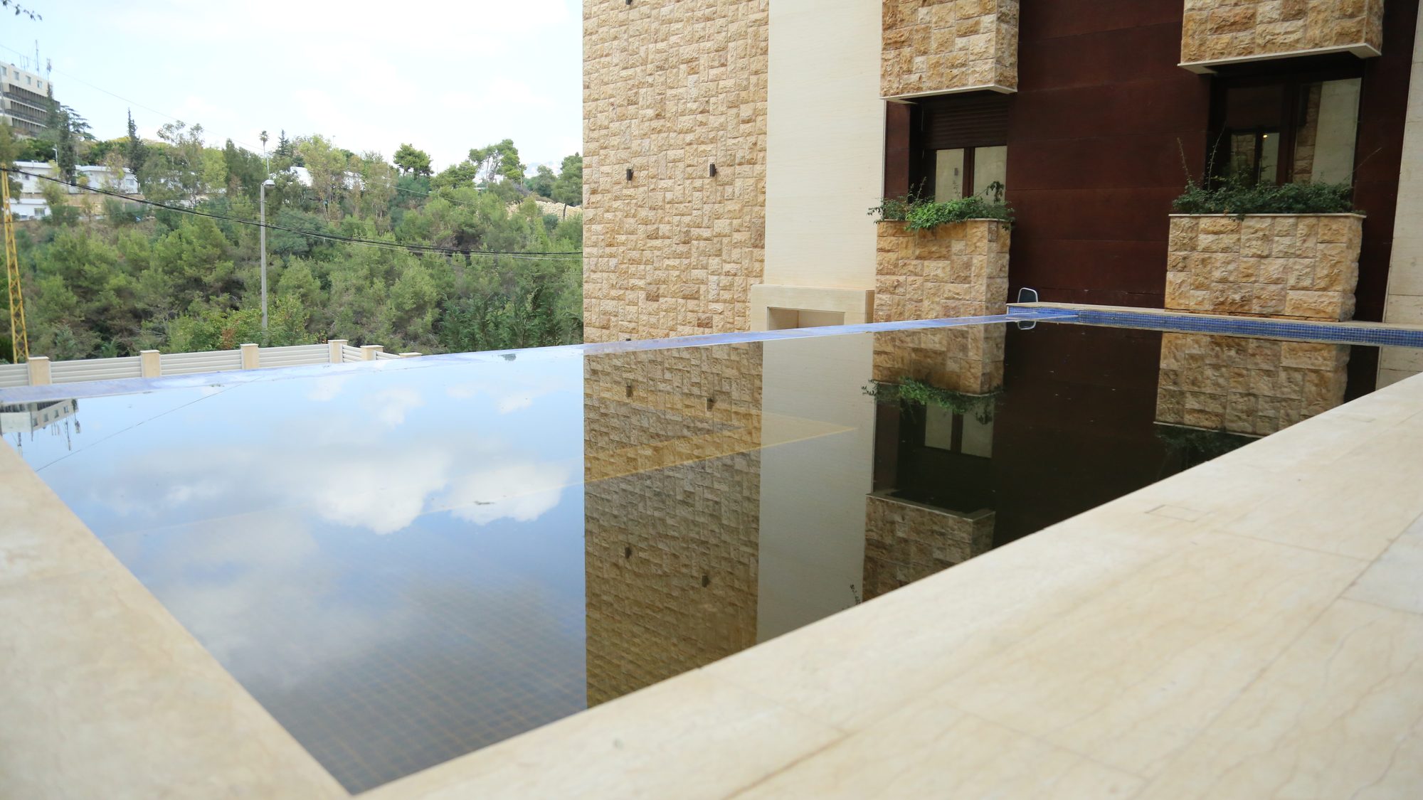 Infinity-edge pool reflecting the stone facades and the sky